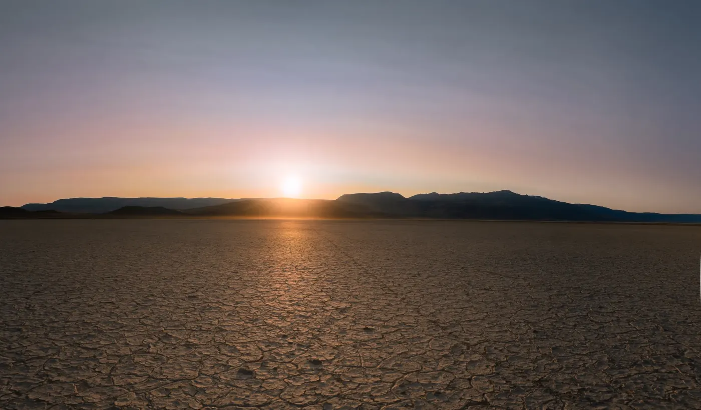 A bright celestial object rising over a desert playa