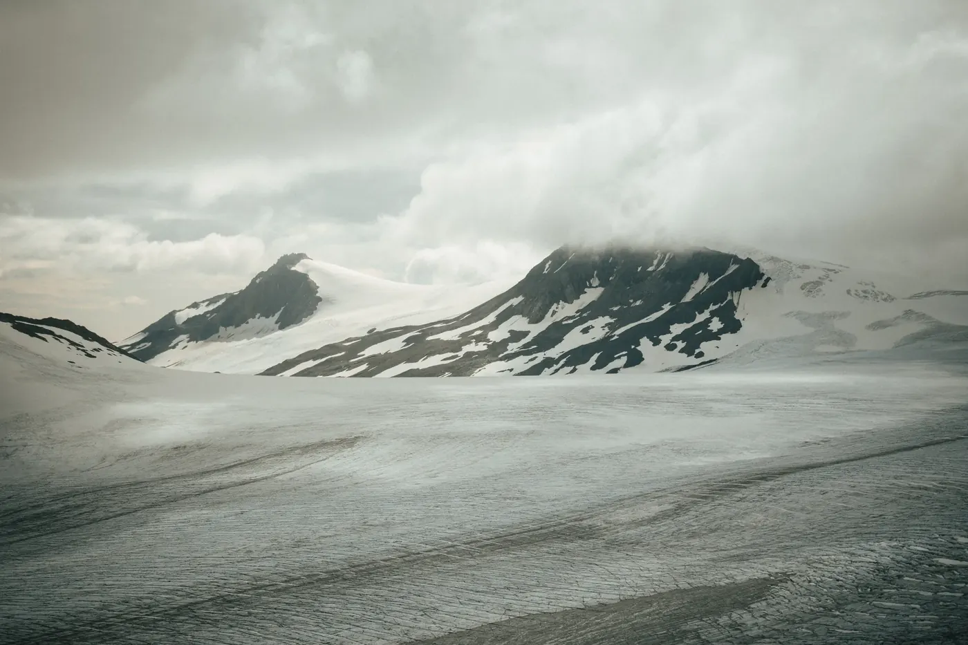 Snow-covered glacial terrain beneath low clouds