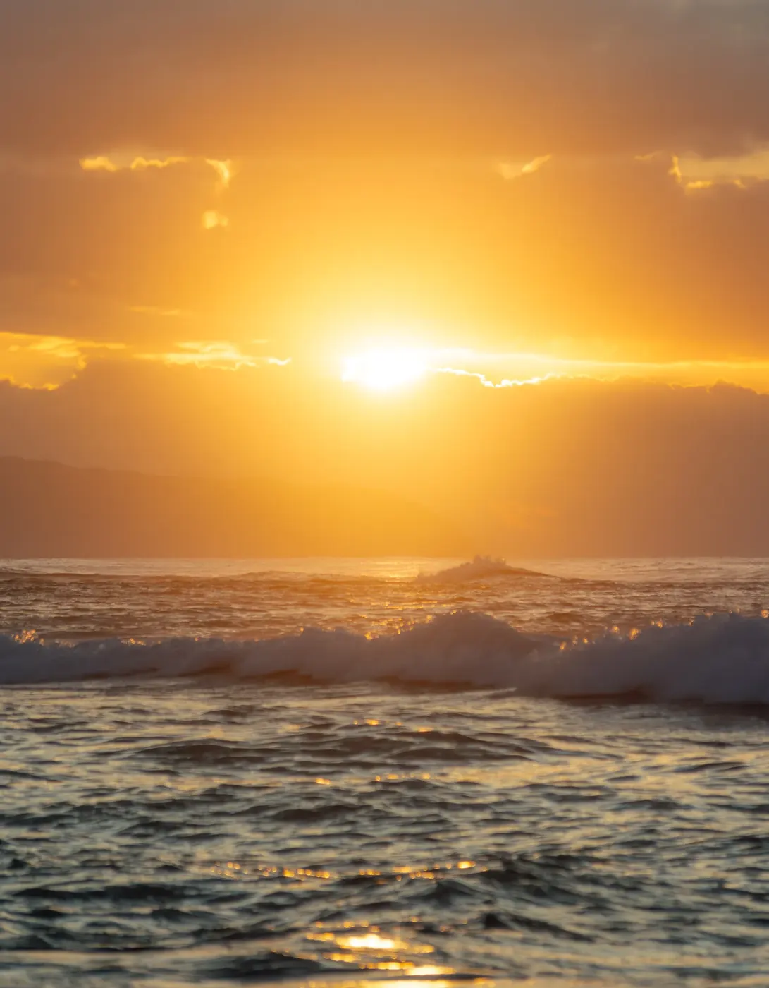 Golden sun above a breaking ocean wave