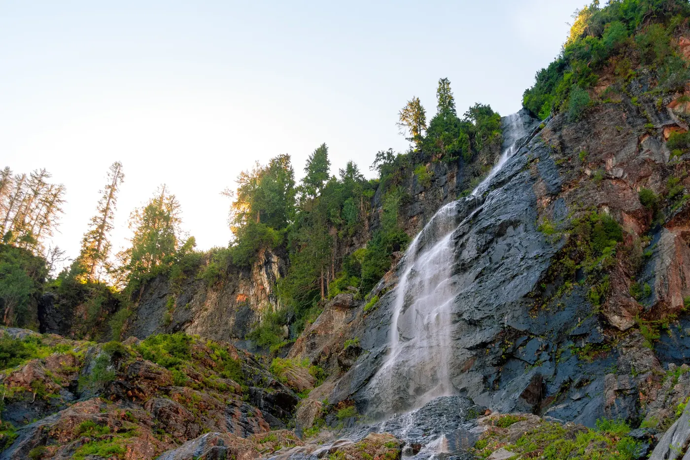 A tall waterfall descending through green mountain terrain