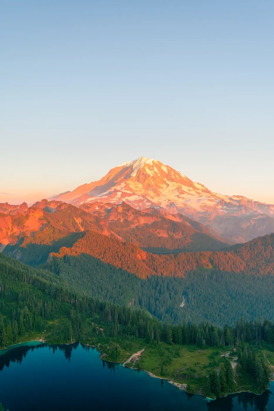 A snow-capped mountain glowing pink at sunset