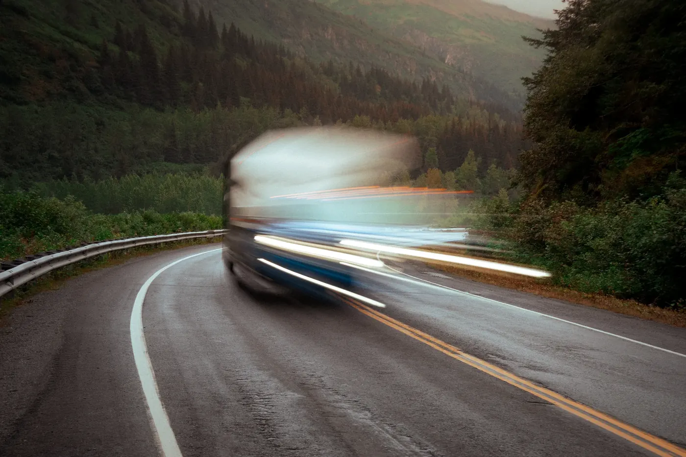 A bus sweeping around a wet mountain road in a blur of motion