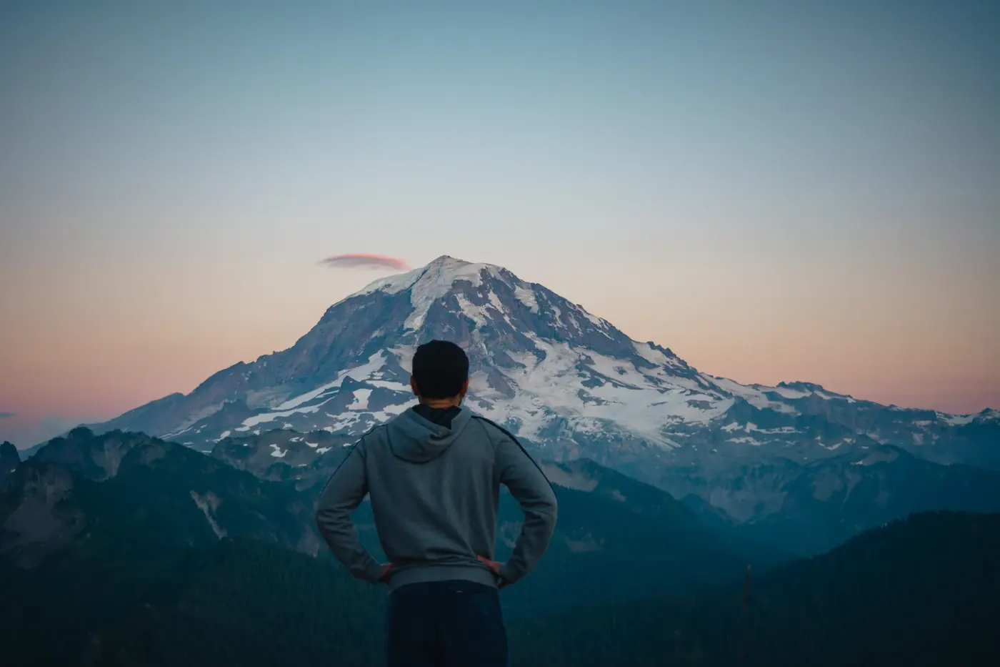 A person looking toward a snow-capped mountain at dusk