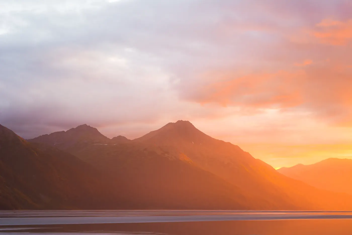 Layered mountain ridges beneath a vivid sunset