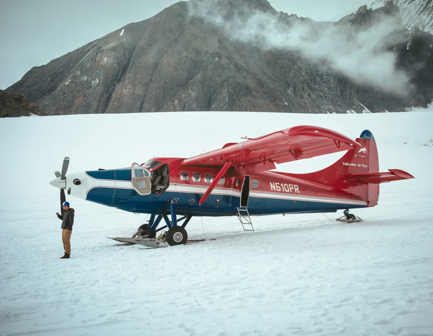 A red aircraft resting on a glacier