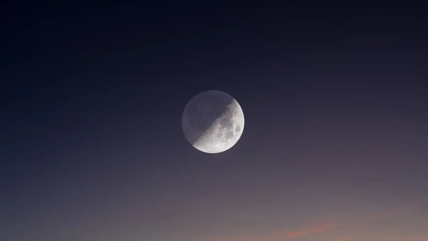 A partial moon in a deep violet evening sky
