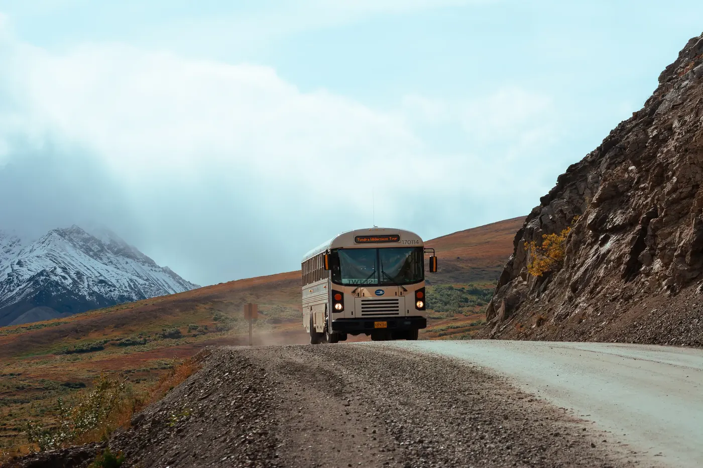A bus traveling along a gravel road through mountain country