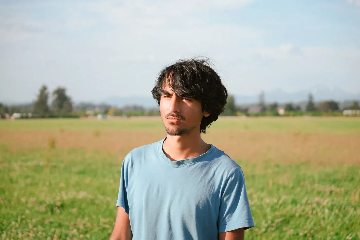 A portrait of a young man in an open field