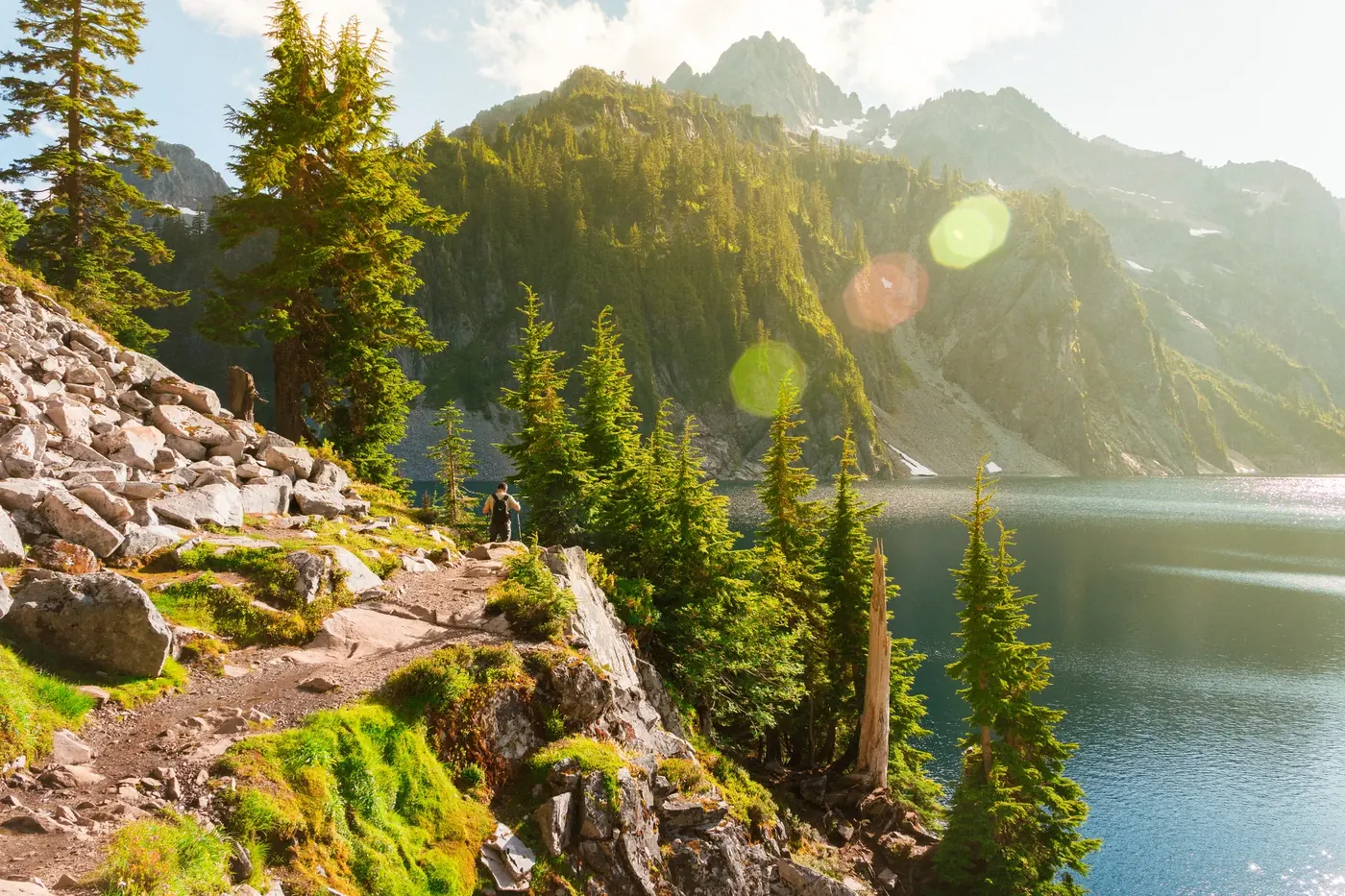Sunlight crossing a mountain lake and evergreen forest