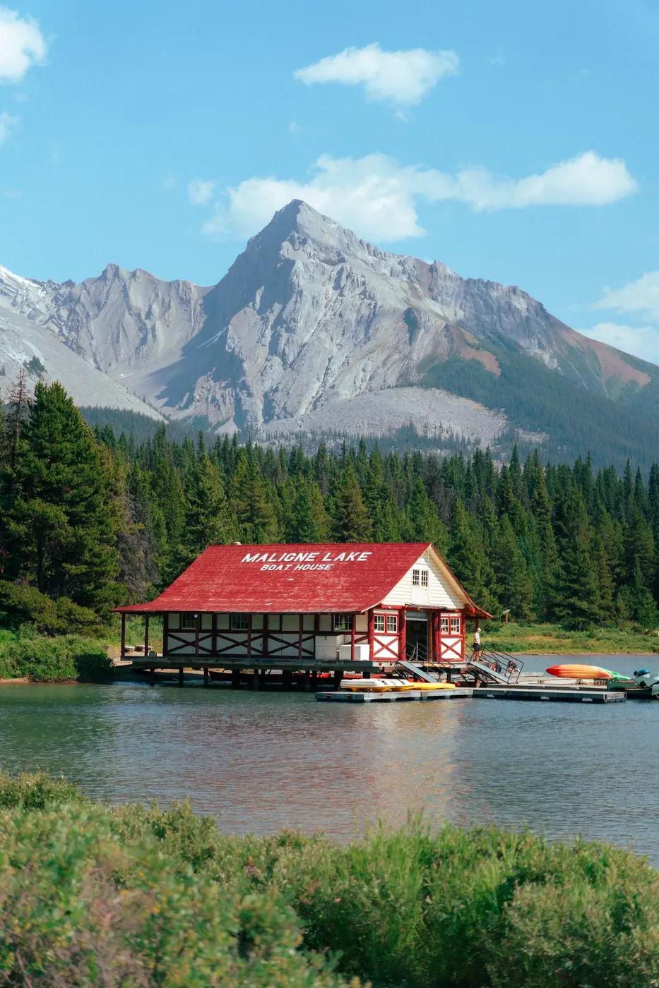 A red-roofed boathouse below a massive mountain