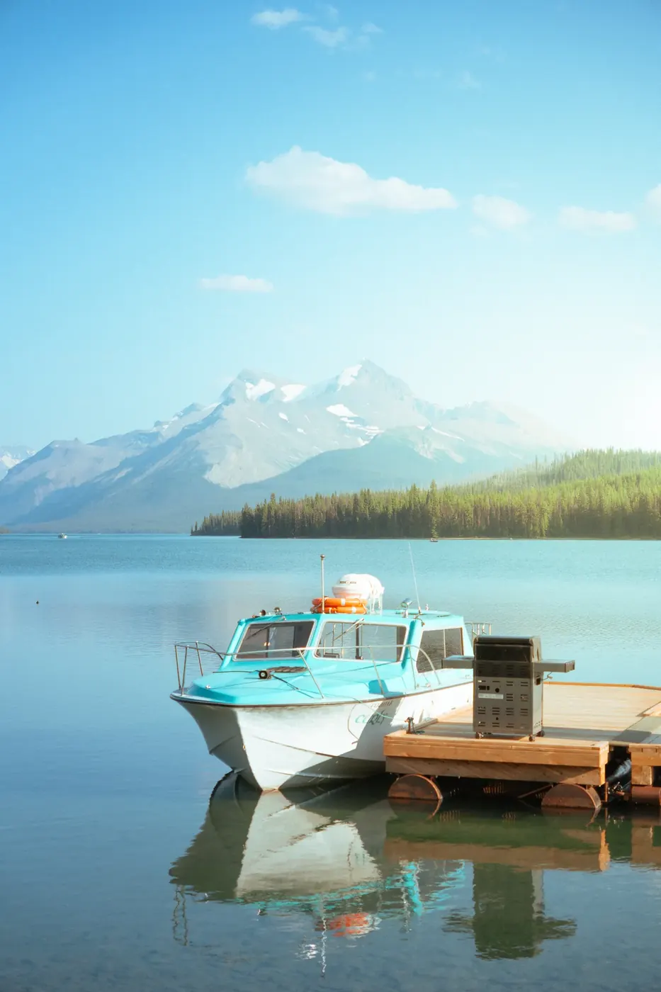 A blue boat crossing a mountain lake