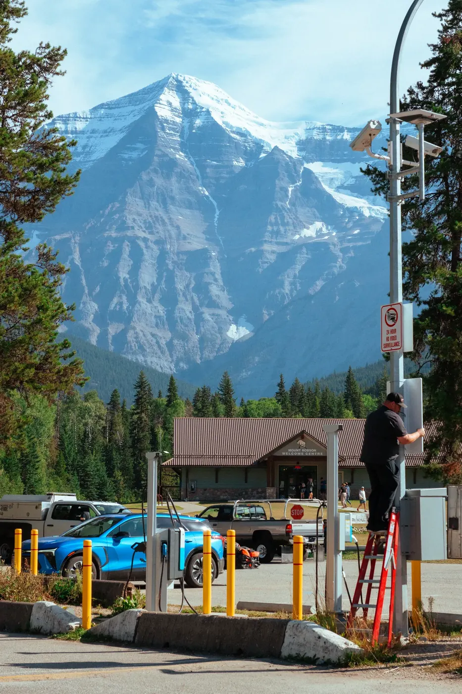 A traveler waiting beneath a mountain at a roadside stop