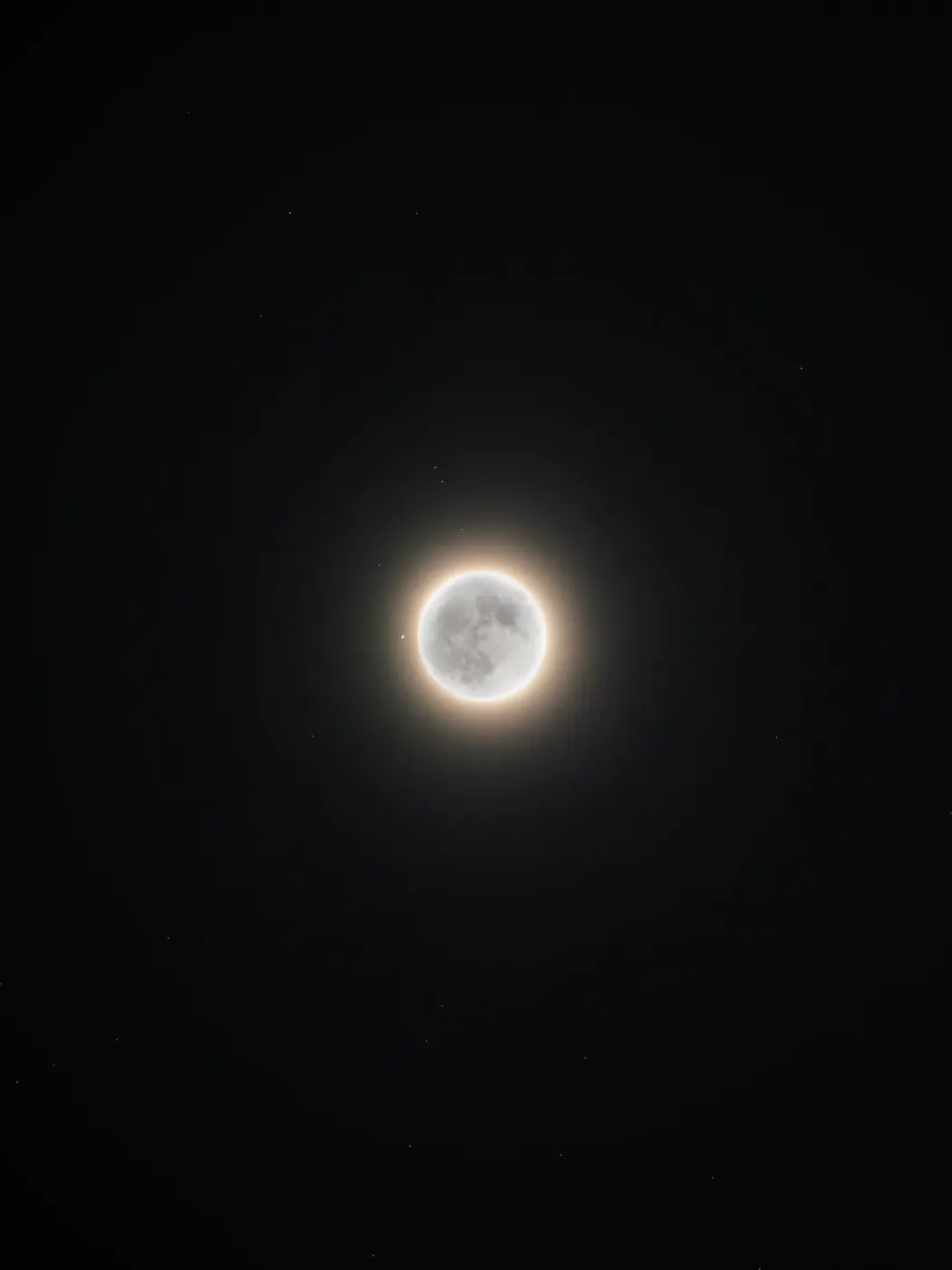 Saturn beside the glowing edge of the moon during an occultation