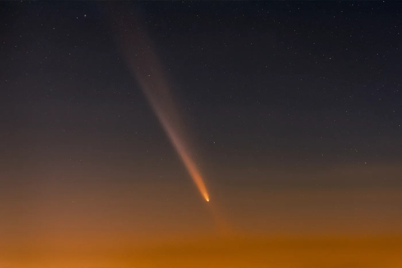 A comet and long tail above a dark horizon
