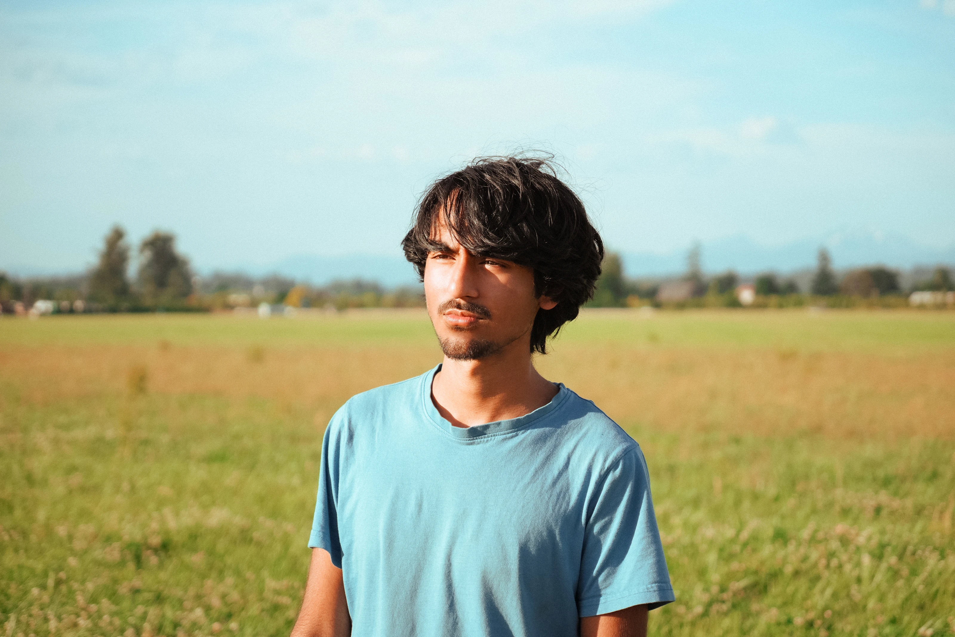Portrait of Adrish Barman standing in a sunlit field